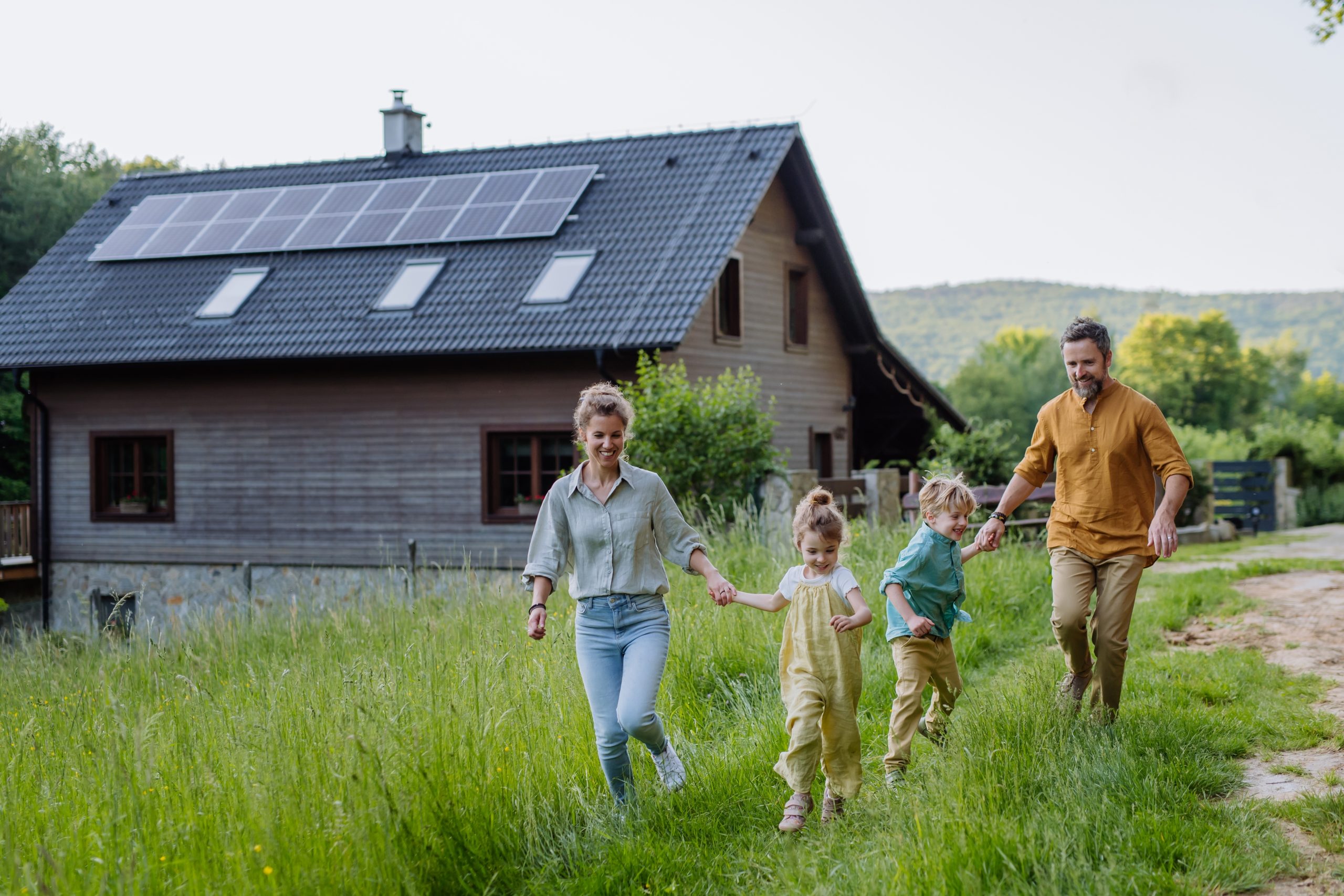 happy,family,in,front,of,their,house,with,solar,panels